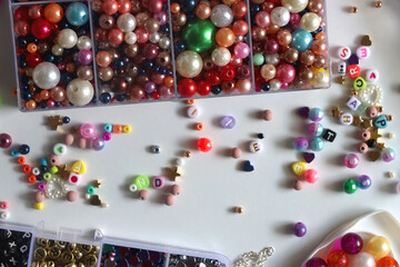 Colorful beads, letter beads, threads and other jewelry making supplies on white background. Making friendship bracelets concept. Flat lay.