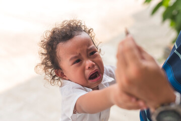 A young male toddler throws a tantrum and cries after his dirty toy is confiscated by his dad.