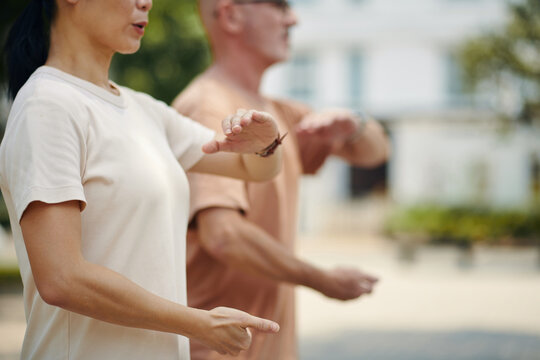 Practicing Tai Chi with a friend outdoors in an urban area wearing casual attire engaging in fluid and concentrated movements for relaxation