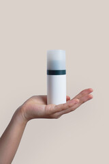 Female hand holding skin care product, Cosmetic white blank bottle cream Hand cream concept . Packaging for cream, gel, serum, advertising and product promotion, mockup