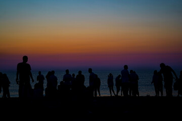 silhouettes. the silhouettes of people waiting for the sunrise by the sea on the beach. Multicolored sky at sunrise by the sea.