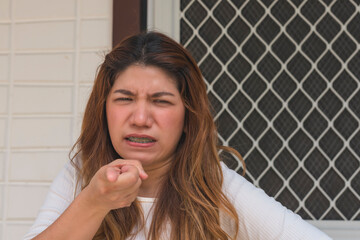 A asian woman in her 30s points at her husband while standing outside the house, demanding to know...