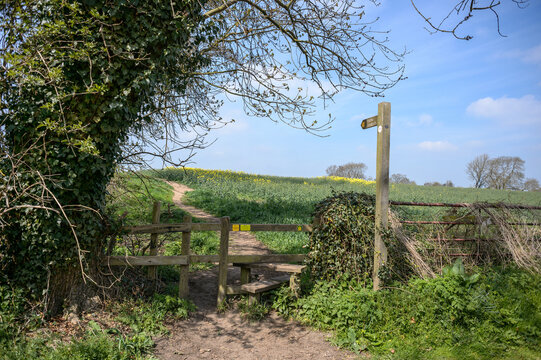 A wooden footpath sign and stile in rural North Yorkshire, UK.