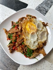 Stir fried Fried Duck Grilled with holy basil served with rice and a fried egg on top of rice, Thai food, street food Thai food spicy fried recipe with cucumber and chili, Pad Kra pao