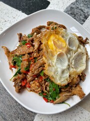 Stir fried Fried Duck Grilled with holy basil served with rice and a fried egg on top of rice, Thai food, street food Thai food spicy fried recipe with cucumber and chili, Pad Kra pao