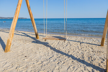  Wooden swing on sandy beach, clear blue sky, tranquil ocean backdrop, serene coastal scene, perfect for relaxation