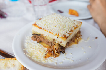 Traditional Greek moussaka served on a rustic restaurant table, showcasing rich, layered Mediterranean flavors