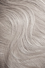 Blond hair close-up as a background. Women's long blonde hair. Beautifully styled wavy shiny curls. Hair coloring. Hairdressing procedures, extension. White hair