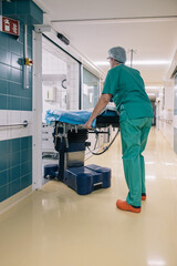 Medical personnel in green uniforms carry a stretcher into the operating room