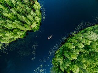 Aerial view of blue lake with boat between green summer woods in Finland.