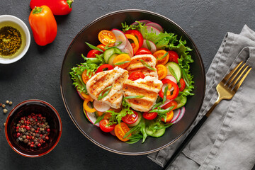 Salad with grilled chicken fillet, fresh green  leaves, cucumber, tomatoes, sweet pepper and radish. Healthy lunch salad in bowl. Top view