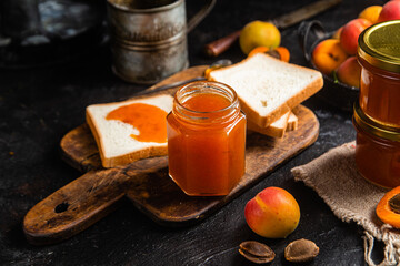 Ripe apricot jam in a glass jar on the table.