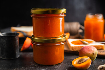 Ripe apricot jam in a glass jar on the table.