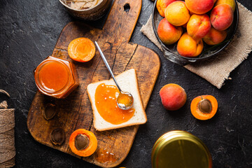 Ripe apricot jam in a glass jar on the table.