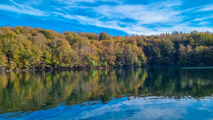 Fototapeta premium Scenic view of water reflections of Kozjak lake in colorful autumn in Plitvice lakes National Park, Karlovac, Croatia, Europe. Idyllic forest in serene beauty of landscape. Tranquil scene in nature