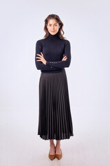 Full length studio shot of a brunette haired woman wearing sweater and skirt against isolated background