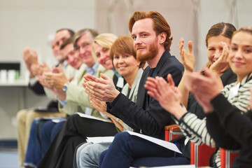 Professionals applauding at business event in auditorium