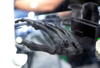 Art Object in form of human skeleton hand printed on 3D printer. Model prototype of skeleton printed on 3D printer from molten plastic on table. FDM 3D printing technology. New additive technologies