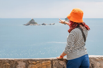 Woman on holiday at viewpoint of Saint Nedjelja island, Montenegro, taking in the natural landscape and clear blue waters