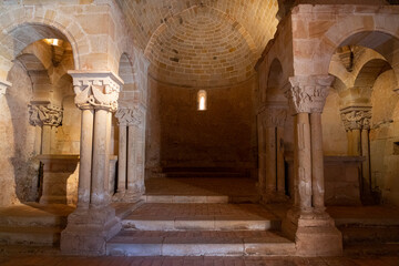 Interior view of a Romanesque church, showcasing intricate stone columns and arches bathed in warm light. Ideal for historical