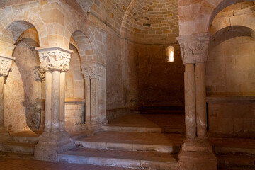 Obraz premium Interior view of a Romanesque church, showcasing intricate stone columns and arches bathed in warm light. Ideal for historical