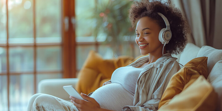 Schwarze schwangere Frau mit Kopfhörer entspannt sich zu Hause
