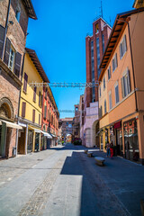 A view down a street leading towards an arched gate in Imola, Italy  in summertime