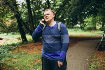 Obraz premium Stress and confused man with problem, error and mistake have conversation in the public park. Frustrated male talking on phone. Summer time. Negative people emotion