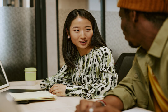 Confident young Asian female CEO discussing project design with African American male employee - Powered by Adobe