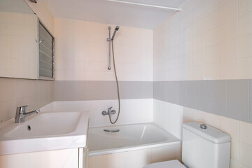 A modern bathroom featuring a bathtub with a shower attachment, a sink, and a toilet with an overall white and gray color scheme, offering a clean and fresh look.