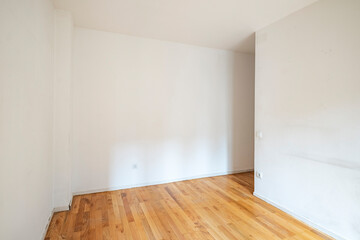 Fototapeta premium A spacious empty room featuring wooden floors and white walls, offering a clean and open space ready to be furnished according to the desired style and purpose.