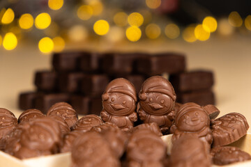 Chocolates in the shape of Christmas figures on the background of a flashing garland