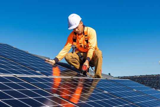 Solar panel technician with drill installing solar panels