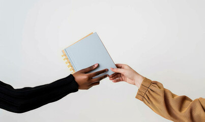 Two hands exchanging a light blue book