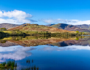 Rural agricultural landscape of mountains  reflected in Scottish loch 