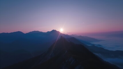 Obraz premium The sun rises above a sea of clouds, casting pastel hues on a mountain peak