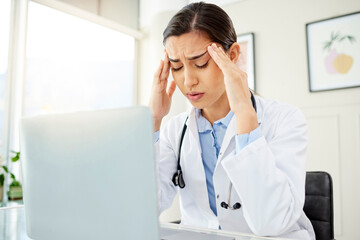 Doctor, woman and laptop with headache from stress in office with burnout, overworked or mental health at desk. Medical, professional or frustrated with migraine, anxiety or ache from clinic overtime