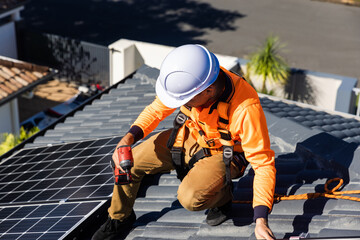 Solar panel technician with drill installing solar panels