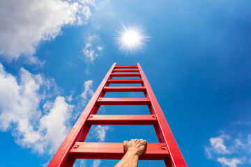The way to the success. Red ladder and a hand reaching to the sky on a blue sky background.