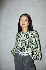 Vertical medium long shot of confident young Asian woman wearing smart casual clothes posing for...
