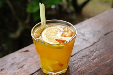 A refreshing glass of Indonesian traditional herbal drink, wedang , garnished with a slice of lemon and lemongrass. Ideal for health drink promotions, traditional remedies, culinary blogs, 