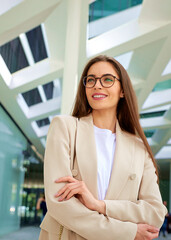 A businesswoman walking on the street in front of a modern office building