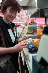A woman is using her cell phone to pay for food at a restaurant. Concept of convenience and...