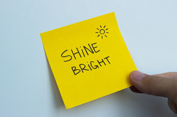 A yellow post-it note that says 'shine bright' with a symbol of the sun in the corner