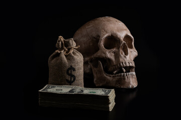 Human skull and a stack of 1 US dollar bills on a black background