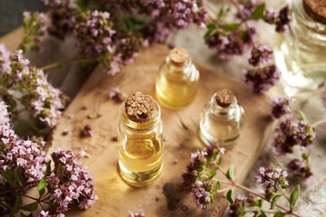 Glass bottles of aromatherapy essential oil with fresh blooming oregano twigs