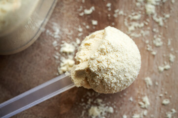 Whey protein powder in a measuring spoon on a table