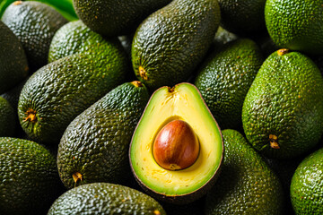 A pile of avocados with one cut open, highlighting the creamy texture and vibrant color avocado tree in the background