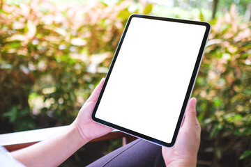 Mockup image of a woman holding digital tablet with blank white desktop screen in the outdoors
