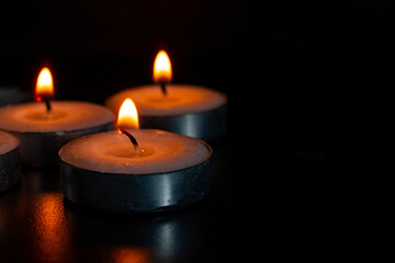 Candles shining on dark background with customizable space for text of message. Copy space concept.